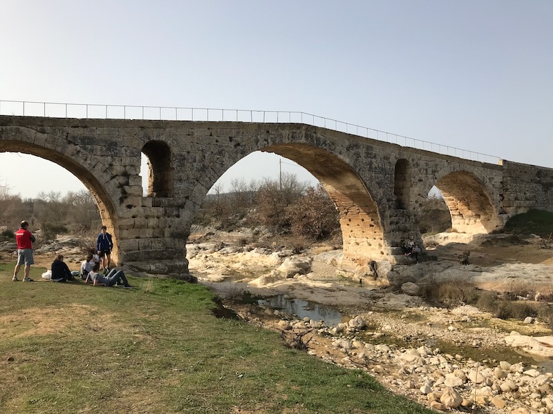 Cyclists relaxing next to the Roman Pont Julien near Bonnieux Cyclists relaxing next to the Roman Pont Julien near Bonnieux
