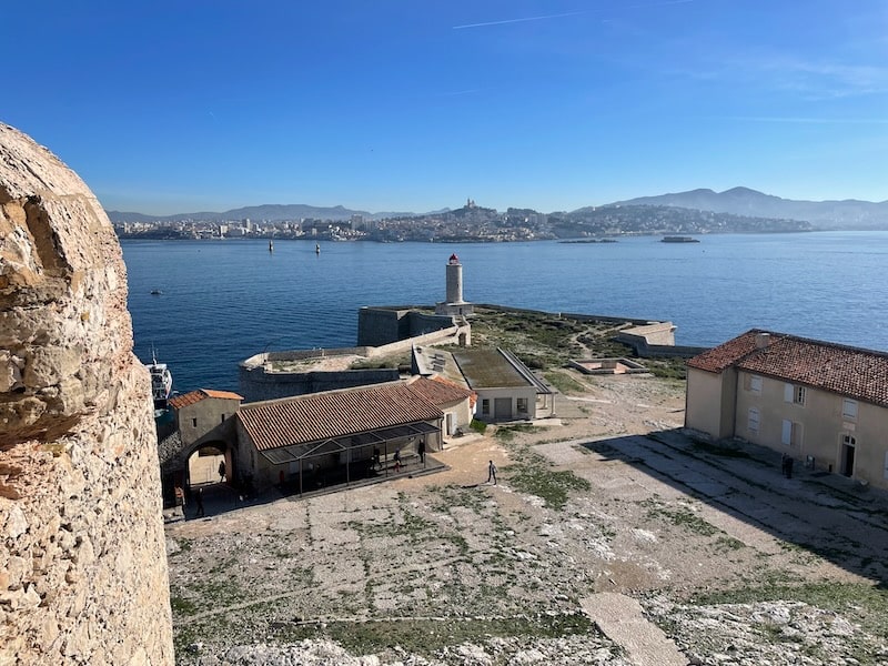 View from the Chateau d'If in Marseille, France, showcasing the distant city skyline and the Vauban barracks on the right.