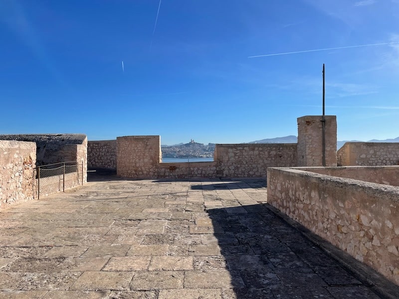 Panoramic view from Chateau d'If rooftop, revealing Marseille across the water, seemingly within reach.
