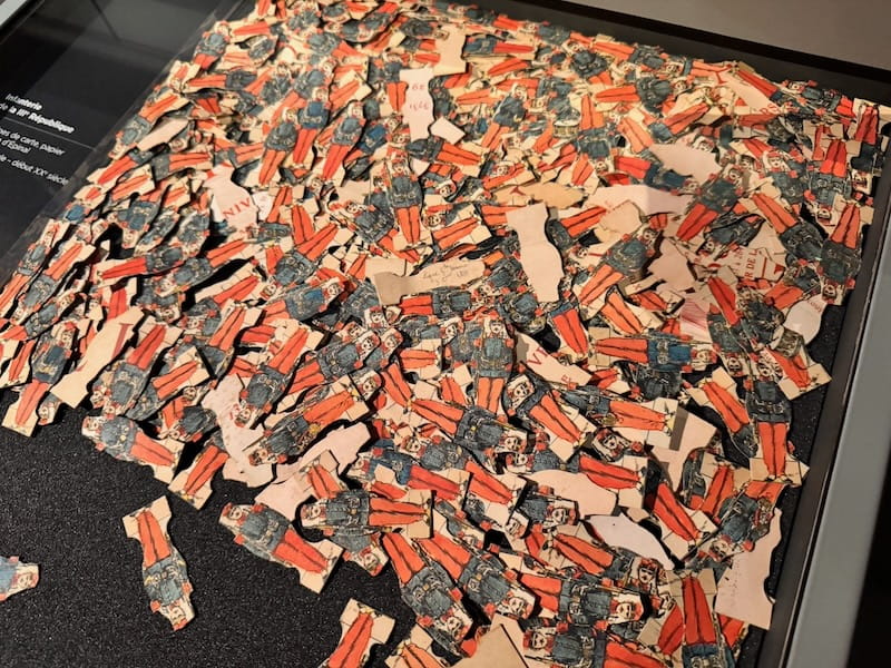Collection of flat paper or cardboard toy soldiers in red trousers and dark blue uniforms at the Musée de la Figurine in Compiègne.