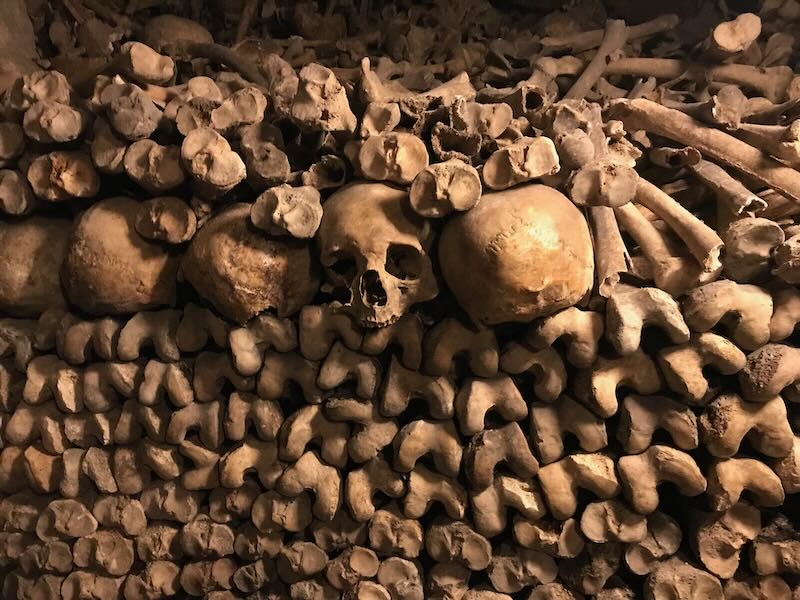 The best catacombs tour Paris will take you through centuries of history underground - with skulls, bones, and dark passageways