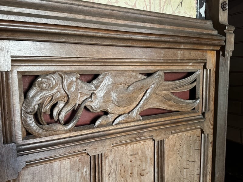 A wooden chimera, part reptile part bird, carved on a wood siding